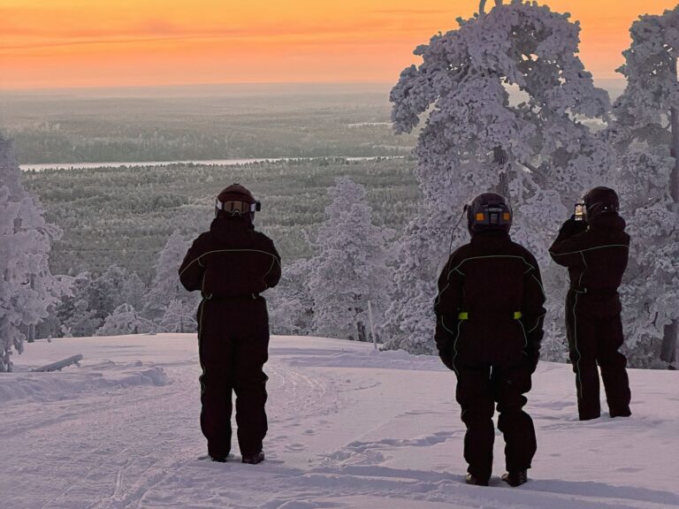 Three riders looking out over the forest and river valley at sunset
